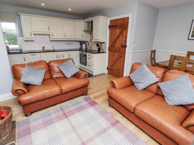 A kitchen with leather sofas and dining area at Rosefinch in Lucker