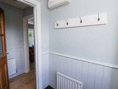 A hallway with wall hooks and radiator at Rosefinch in Lucker