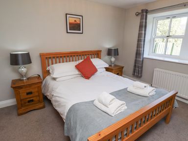 A bedroom with a bed and bedside tables at Rosefinch in Lucker