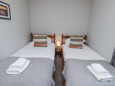 A bedroom with two single beds and a lamp at Rosefinch in Lucker