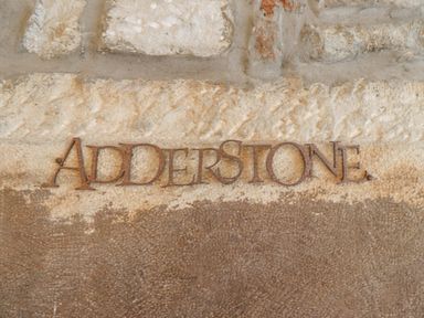 A close up of a stone wall with the word addersone made of metal attached to it at Adderstone Cottage Bamburgh