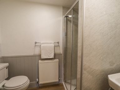 A bathroom with a toilet towel rack radiator and a shower at Adderstone Cottage in Bamburgh