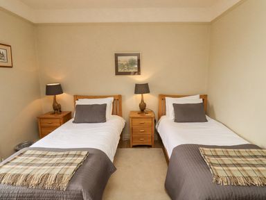 A bedroom with two single beds nightstands and lamps at Adderstone Cottage in Bamburgh