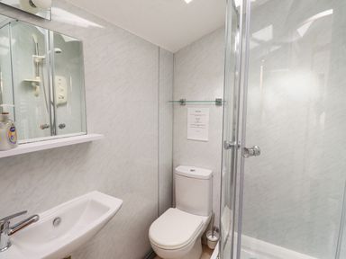 A bathroom with a sink mirror soap dispenser toilet and shower at Adderstone Cottage in Bamburgh