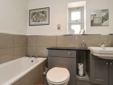 A bathroom with a bathtub toilet sink and a small window at Adderstone Cottage Bamburgh