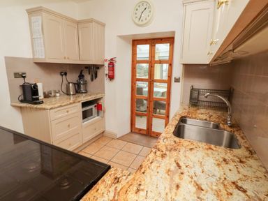 A kitchen with a sink and microwave at Adderstone Cottage in Bamburgh