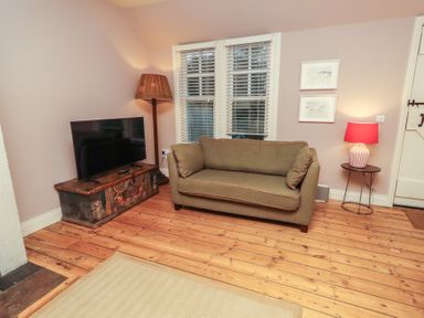 A living room with a sofa and television at Armstrong Cottages No6 Bamburgh