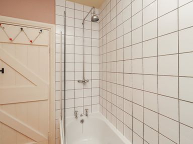 A bathroom with a bathtub and shower at Armstrong Cottages No6 Bamburgh