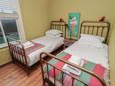 A bedroom with two beds and a nightstand at Armstrong Cottages No6 Bamburgh