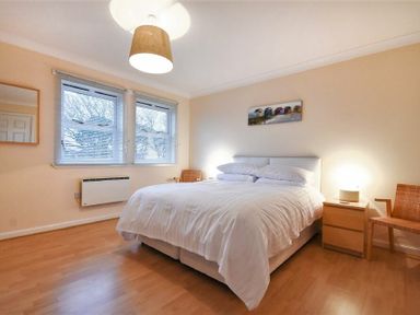 A bedroom with a bed white bedding bedside table lamp and two chairs at Beachcomber Apartment Bamburgh