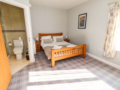 A bedroom with a bed and attached bathroom at Pipistrelle in Bamburgh