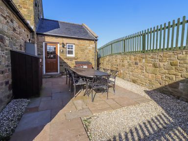 An outdoor seating area with a table and chairs at Goosander in Bamburgh