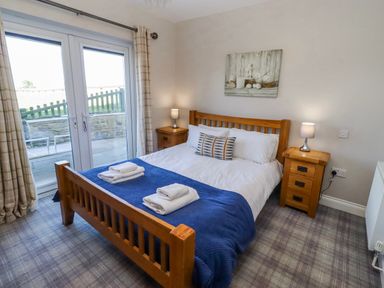 A bedroom with a double bed and bedside tables at Goosander in Bamburgh