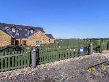 A house with a green fence and gate at Goosander in Bamburgh
