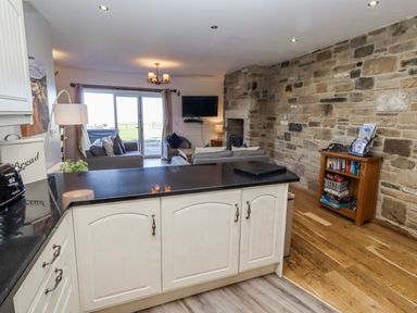 A kitchen with a counter and living area at Jackdaw in Bamburgh