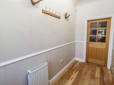 A hallway with hooks on the wall and a door at Jackdaw in Bamburgh
