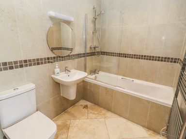 A bathroom featuring a toilet, sink, mirror, shower, and bathtub at Jackdaw in Bamburgh
