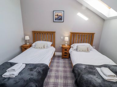 A bedroom with two single beds and a picture on the wall at Jackdaw in Bamburgh