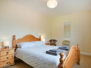 A bedroom with a wooden bed frame and bedside tables with lamps at Decked Out in Alnmouth