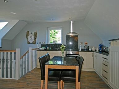 A kitchen with a dining table and chairs a stove and a window at Quarry Mews in Bamburgh