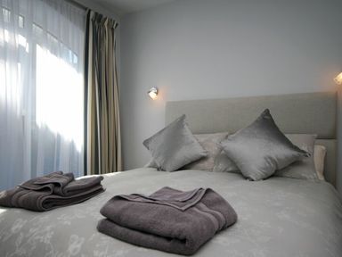 A bedroom with a bed made with pillows and folded towels by the window at Quarry Mews in Bamburgh