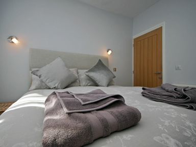 A bedroom with a bed that has gray pillows and folded towels at Quarry Mews in Bamburgh