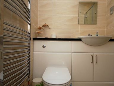 A bathroom with a toilet sink a mirror and a towel radiator at Quarry Mews in Bamburgh