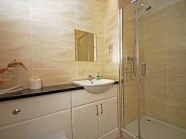 A bathroom with a sink mirror shower enclosure and toilet paper on the counter at Quarry Mews in Bamburgh