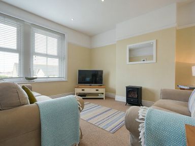 A living room with two sofas a television on a stand and a small electric fireplace at Coastal Haven in Seahouses
