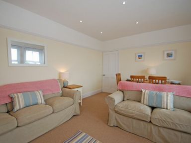 A living room with two beige sofas and a dining table with wooden chairs at Coastal Haven in Seahouses