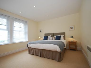 A bedroom with a double bed two bedside tables and a window with blinds at Coastal Haven in Seahouses