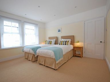 A bedroom with two single beds a bedside table and two large windows at Coastal Haven in Seahouses