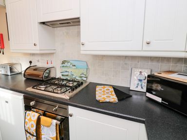 A kitchen countertop with a gas stove oven toaster breadbox microwave and cookbook at Arcadie in Amble
