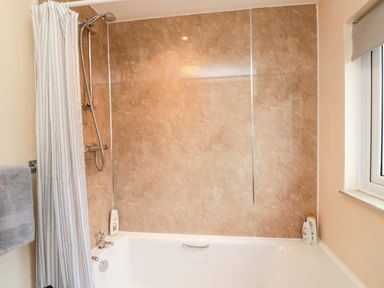 A bathroom with a bathtub shower and a window at Arcadie in Amble