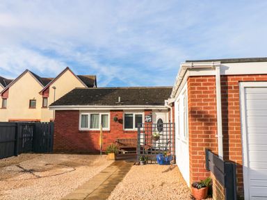A small brick house with a bench near the door and a gravel driveway at Arcadie in Amble