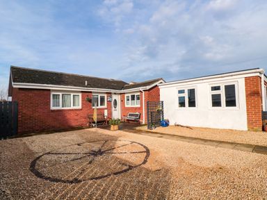 A single story brick and white exterior house with gravel driveway and benches at Arcadie in Amble