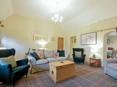A living room with chairs sofa and wooden trunk table at Charlton Cottage in Bamburgh