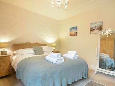 A bedroom with a bed covered in a light blue blanket and white towels on top at Charlton Cottage in Bamburgh
