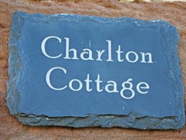 A stone plaque with the text Charlton Cottage mounted on a brick wall at Charlton Cottage Bamburgh