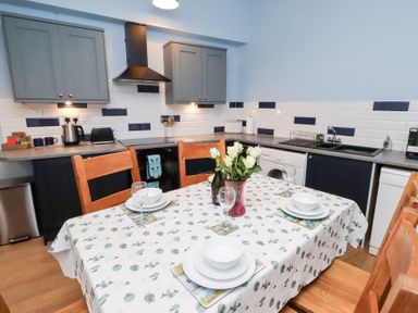 A kitchen with a table setup and appliances at Riverside Cottage Warkworth