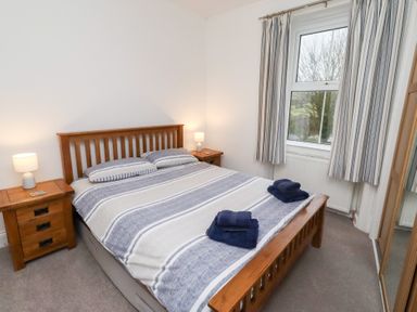 A bedroom with a bed and nightstands at Riverside Cottage in Warkworth