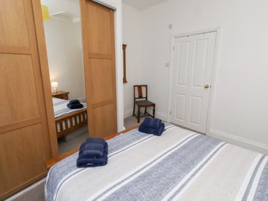 A bedroom with a bed and wardrobe at Riverside Cottage in Warkworth