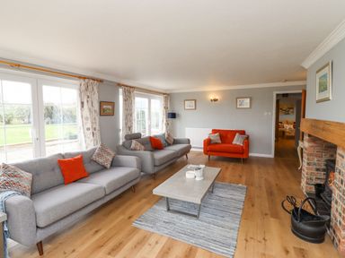 A living room with grey and red sofas a coffee table a fireplace and large windows at Jara in Bamburgh