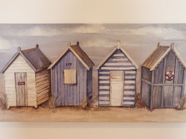 A painting of four small beach huts in a row with different designs and colors