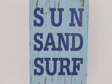 A wooden sign with the words sun sand surf painted in blue on a light blue background at Jara in Bamburgh