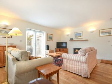 A living room with sofas coffee table television and wood flooring at Stone Cottage in Bamburgh