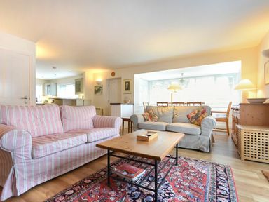 A living room with striped and plain sofas a wooden coffee table and a patterned rug at Stone Cottage in Bamburgh
