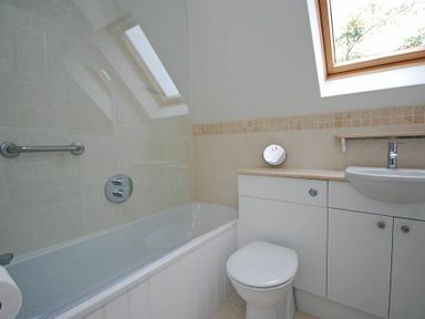 A bathroom with a bathtub toilet sink under a skylight window at Stone Cottage in Bamburgh