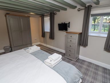 A bedroom with a bed, wardrobe, television and towels at Old Mill (Lucker)
