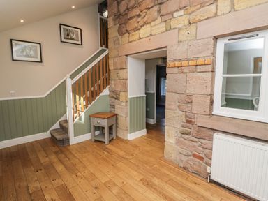 A hallway with a staircase and side table at Millstone in Lucker